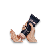LuxNaura UNOVE Deep Damage Treatment EX hair mask in a dark blue tube being squeezed into a hand for application.