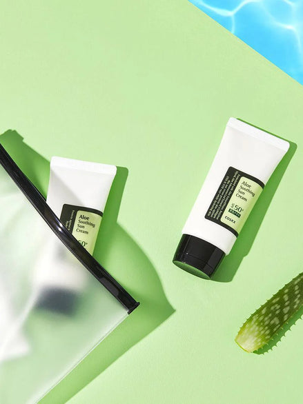 Two tubes of aloe vera cream on a green background with a slice of cucumber.